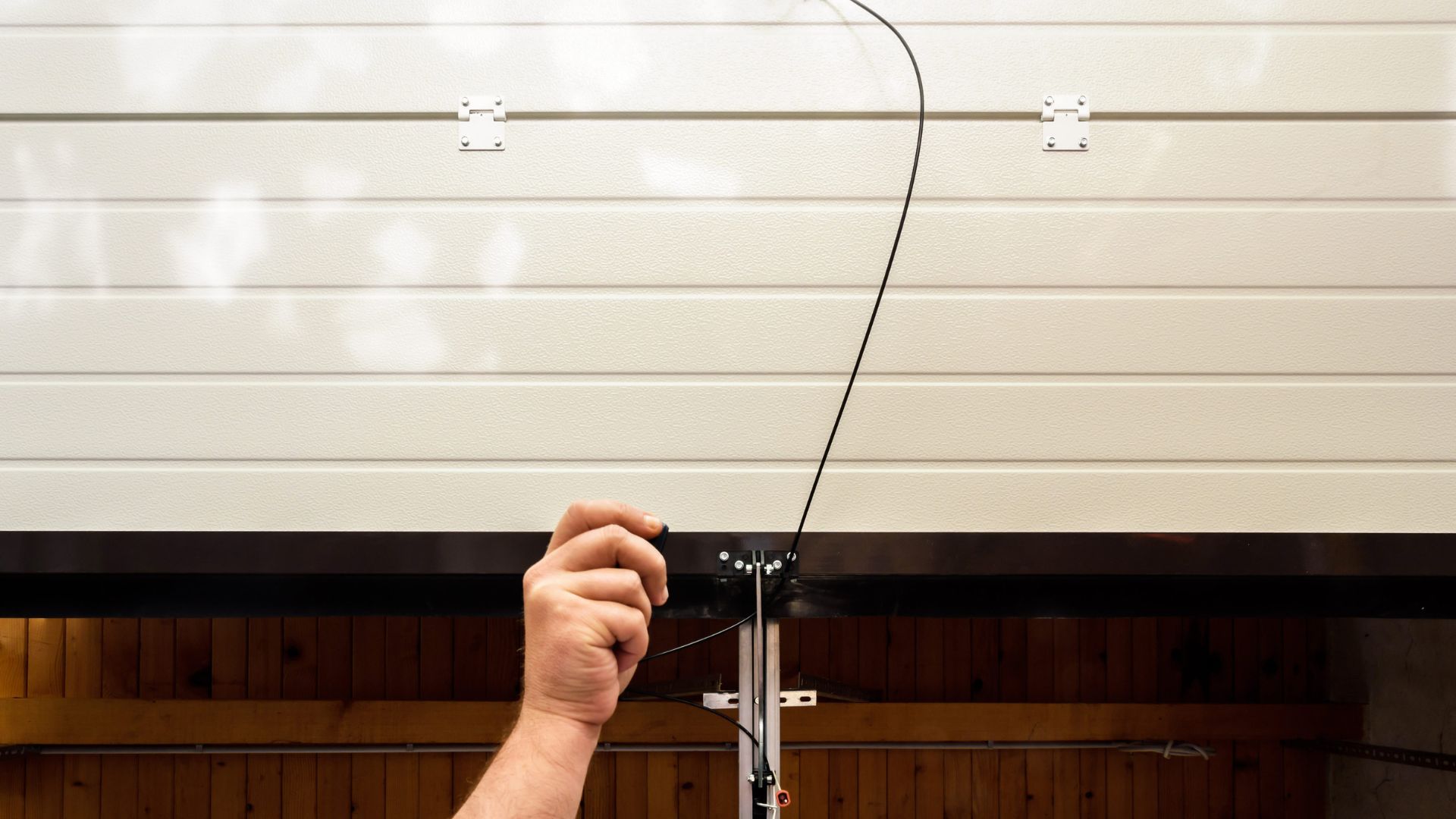 A hand is holding a television antenna in front of a wall